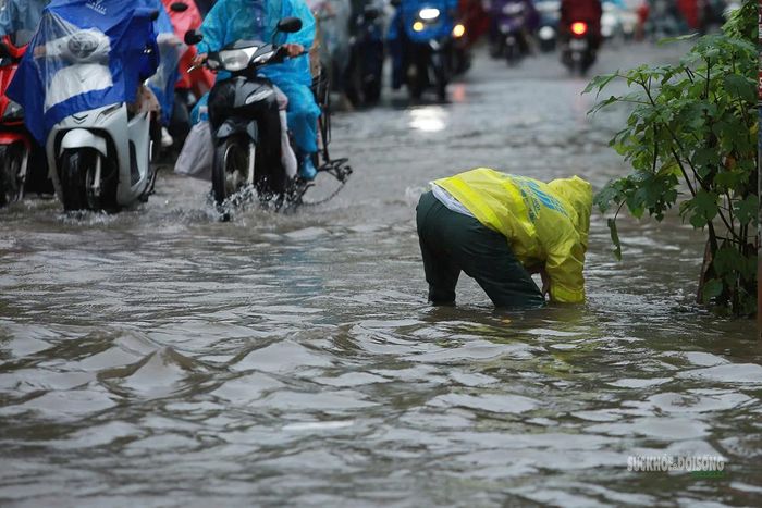 Lực lượng thoát nước kiểm tra hệ thống tiêu thoát giữa đoạn đường ngập sâu. Ảnh: T.Anh