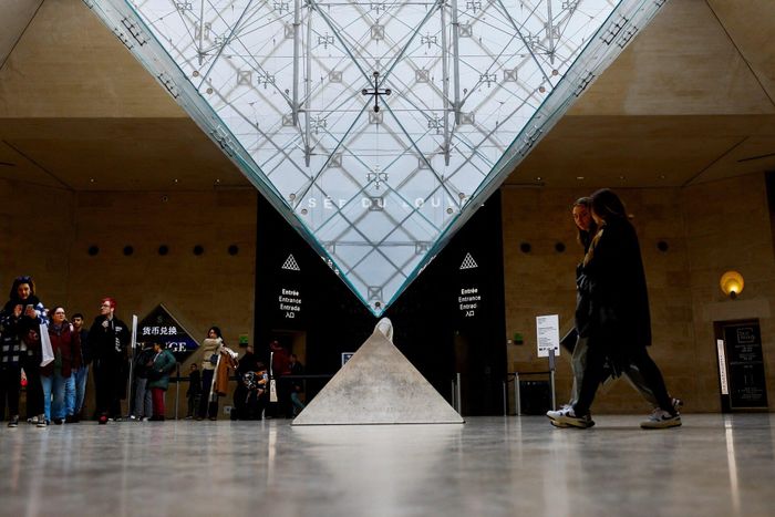 Du khách đi bộ gần kim tự tháp kính của Bảo tàng Louvre ở Paris (Pháp). Ảnh: Gonzalo Fuentes/Reuters.