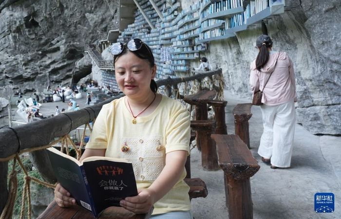 Dù đặt ngoài trời, sách tại đây ít chịu tác động trực tiếp của mưa. Theo He Zhijian, cấu trúc tự nhiên của hố sụt và phần vách đá phía trên tạo thành một lớp che chắn, giúp khu vực đặt sách tránh phần lớn gió mưa. Du khách có thể ngồi đọc trên những chiếc ghế bố dọc lối đi, trong khi ngay gần đó còn có quán cà phê nhìn ra hố sụt. Ảnh: Long Tao/Xinhua.