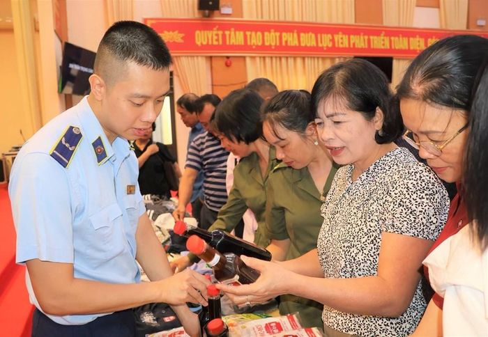 Cán bộ quản lý thị trường hướng dẫn đại biểu, người dân nhận diện, phân biệt hàng thật, hàng giả tại Hội nghị
