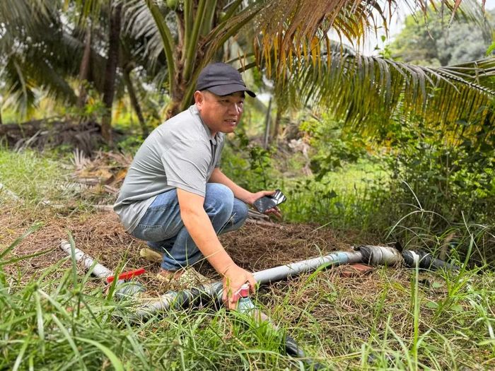 Anh Lê Đức Hòa vận hành hệ thống tưới nước cho vườn cây trong mô hình kết hợp trồng cây và nuôi cá tại xã Lộc Ninh, tỉnh Tây Ninh. (Ảnh: ANH TRƯỜNG-MAI TẠO)