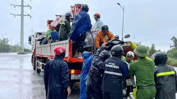 Công an phường Nghi Sơn hỗ trợ người cùng phương tiện di chuyển qua điểm ngập nước. (Ảnh: Công an Thanh Hóa)