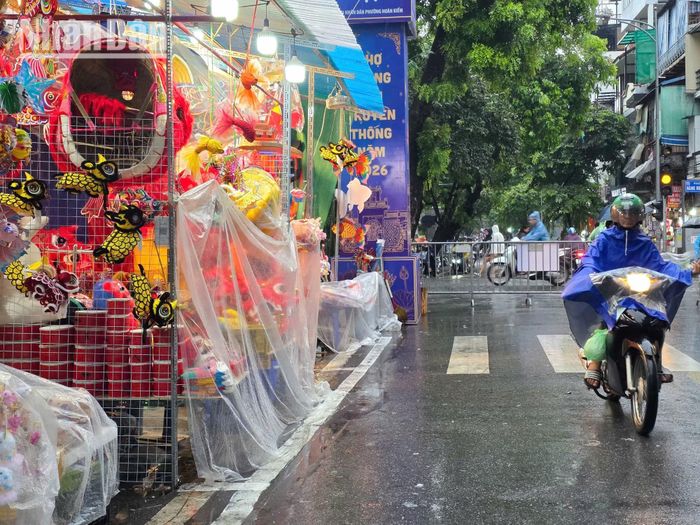 Dù trời mưa, hoạt động buôn bán tại khu vực phố cổ vẫn tiếp diễn. Người bán tìm cách che chắn hàng hóa, còn người mua tranh thủ hoàn tất công việc trước khi trở về nhà.