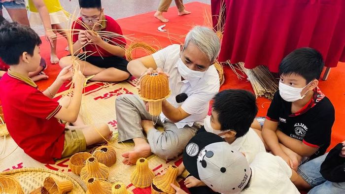 Các em nhỏ cùng nghệ nhân làm sản phẩm thủ công truyền thống. (Ảnh: Ban tổ chức)