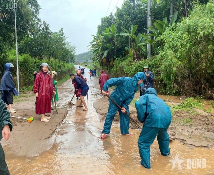 Dân quân xã Tuyên Sơn cùng người dân dọn đất, cát trên đường. 