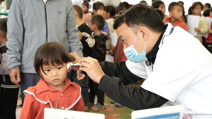 Bác sĩ khám tai cho học sinh trong chương trình khám sức khỏe, sàng lọc miễn phí tại xã Sơn Vĩ. 