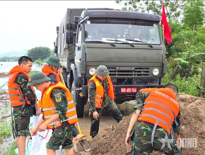 Cán bộ, chiến sĩ Lữ đoàn Xe tăng 201 giúp dân gia cố tuyến đê. Ảnh: VĂN HẢI
