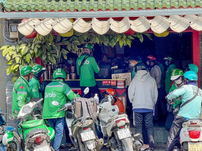 Các tài xế xe công nghệ chờ nhận món khách đặt qua ứng dụng tại một cửa hàng trên đường Tôn Đản, phường Khánh Hội, TPHCM. Ảnh: HOÀNG HÙNG