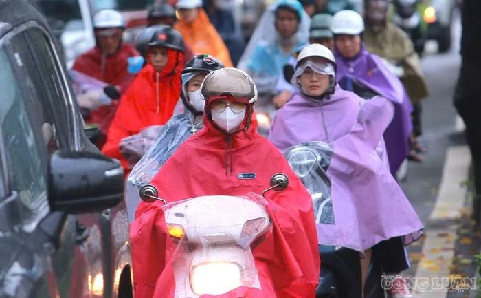 Thời điểm này, Hà Nội có mưa rả rích từ đêm đến sáng sớm. Người dân mặc áo mưa, di chuyển đến nơi làm việc trong điều kiện thời tiết không thuận lợi.