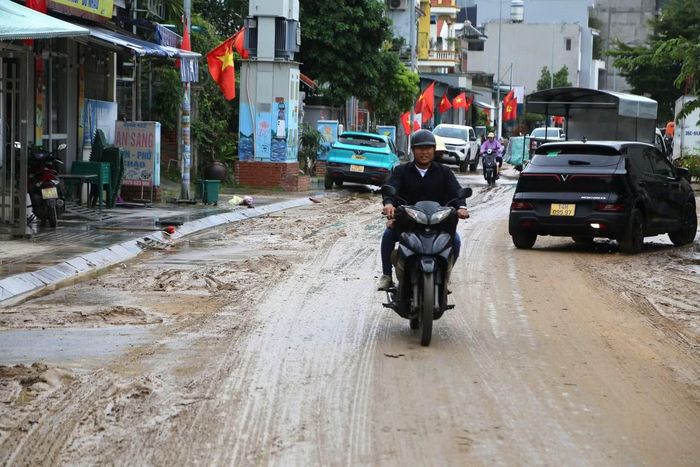 Lớp bùn nhão bị phương tiện cán qua tạo thành những rãnh sâu. Người đi xe máy phải giảm tốc độ, lựa những vị trí ít bùn để di chuyển vì mặt đường trơn trượt.