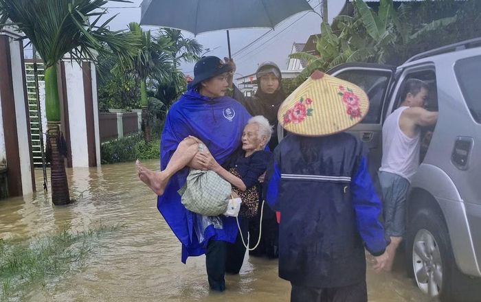 Đơn vị chức năng xã Nghĩa Lộc hỗ trợ bế một cụ già ra khỏi nhà bị ngập nước.