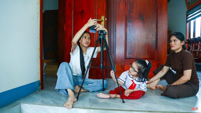 Trước mỗi lần quay video, mẹ và chị chuẩn bị điện thoại, chân máy rồi đặt ở vị trí vừa tầm để em dễ nhìn vào ống kính. Mọi thứ được sắp xếp gọn gàng để em thoải mái bắt đầu câu chuyện trước máy quay. Với những thiết bị đơn giản ấy, trung bình mỗi tháng hai mẹ con thực hiện khoảng 50 video đăng tải trên mạng xã hội.