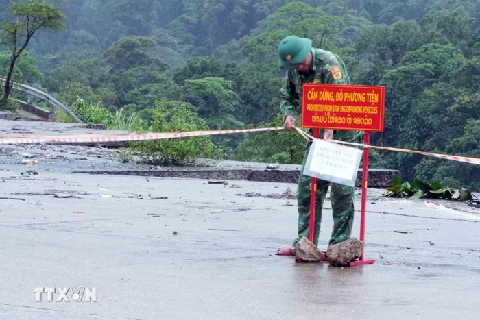 Lực lượng chức năng đặt biển cảnh báo khu vực nguy hiểm tại vị trí sạt lở. (Ảnh: Tá Chuyên/TTXVN)