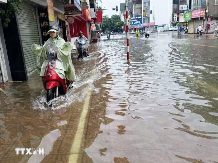 Ngập úng trên phố Ngọc Lâm, phường Bồ Đề, khiến việc đi lại của người dân gặp nhiều khó khăn. (Ảnh: Minh Quyết/TTXVN)