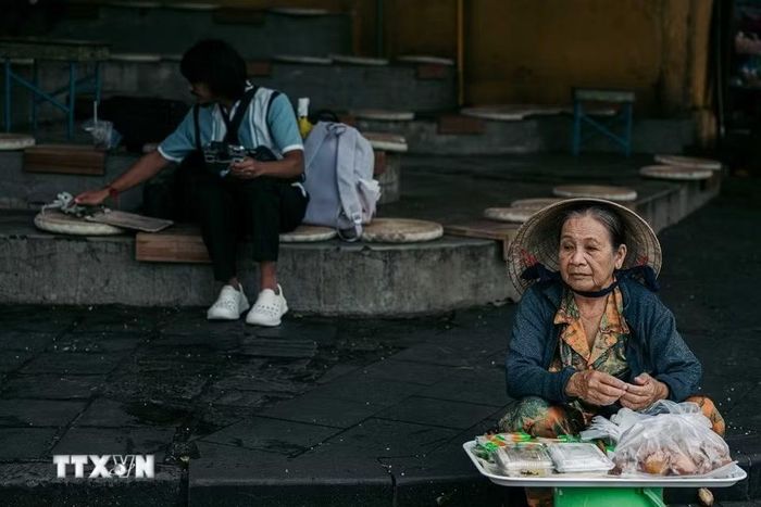 Một người phụ nữ lớn tuổi bán hàng bên hiên phố cổ. Chính những sinh hoạt bình dị của cư dân đã khiến Hội An không chỉ là quần thể kiến trúc được bảo tồn mà còn là một di sản sống được tiếp nối qua nhiều thế hệ. (Ảnh: Phạm Tuấn Anh/TTXVN)