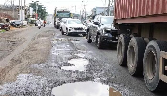 Mặt đường Nguyễn Huệ loang lổ với nhiều hố sâu đọng nước, khiến các phương tiện phải di chuyển qua những đoạn đường hư hỏng trong điều kiện giao thông đông đúc.