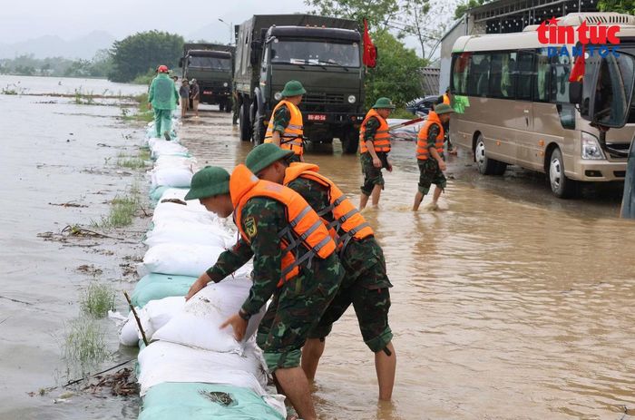Tại một số vị trí nước đã tràn qua mặt đê, lực lượng xung kích phòng, chống thiên tai, người dân địa phương cùng 130 cán bộ, chiến sĩ quân đội khẩn trương xúc cát vào bao, xếp thành hàng chống tràn, phủ bạt hạn chế dòng nước xói mặt và mái đê.