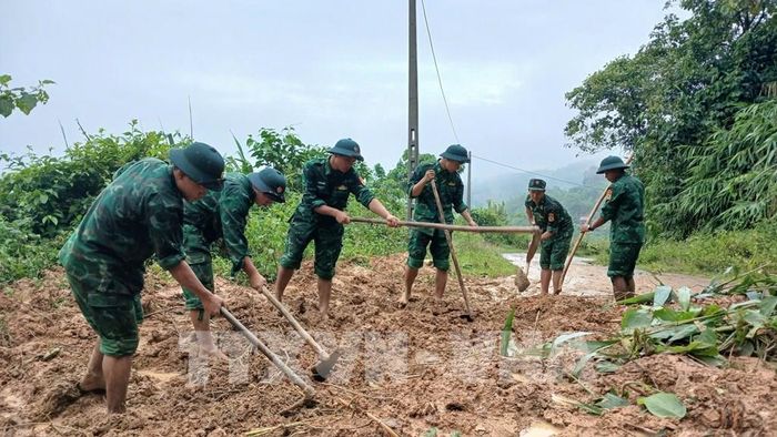 Lực lượng Bộ đội Đồn Biên phòng Ba Nang (Quảng Trị) dọn dẹp đất đá tại vị trí sạt lở, khẩn trương khơi thông tuyến đường phục vụ việc đi lại và hỗ trợ người dân. Ảnh: TTXVN phát