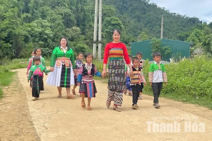 Cô giáo Thao Thị Kía (mặc trang phục dân tộc Mông, người đi sau) đã có 12 năm gắn bó với các em học sinh mầm non bản Mùa Xuân.