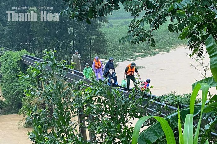 Lực lượng chức năng vượt qua suối Khe Me vào thôn Hợp Tiến hỗ trợ sản phụ.