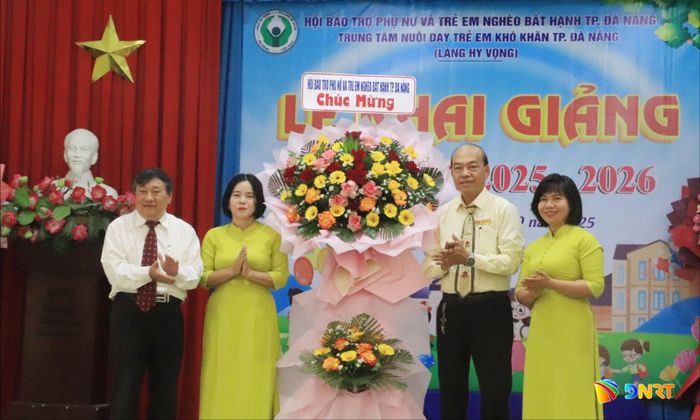 Chủ tịch Hội Bảo trợ phụ nữ và trẻ em nghèo bất hạnh thành phố Huỳnh Văn Hoa (ngoài cùng bên trái) tặng hoa chúc mừng lễ khai giảng năm học 2025 - 2026 tại Làng Hy Vọng. Ảnh: ĐẮC MẠNH