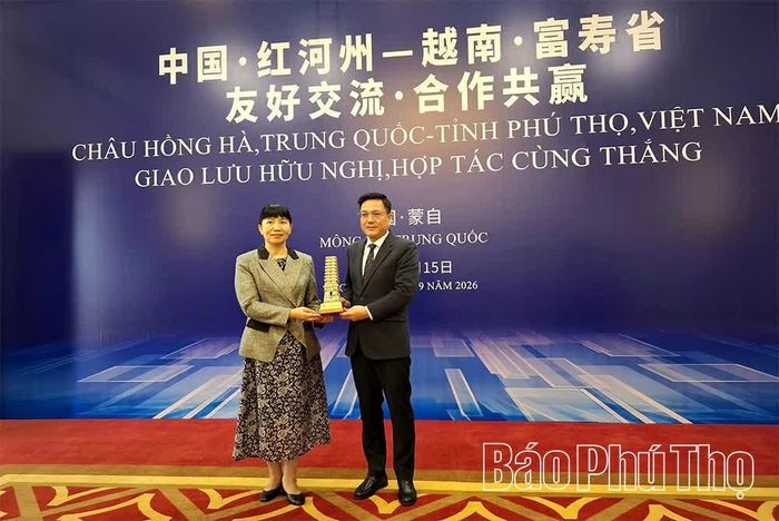 Phó Chủ tịch UBND tỉnh Vũ Việt Văn trao quà lưu niệm tặng bà La Bình - Phó Bí thư Châu ủy, Châu trưởng Châu Hồng Hà.