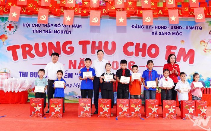 Đồng chí Trưởng Ban Tổ chức Tỉnh ủy và lãnh đạo Hội Chữ thập đỏ tỉnh trao quà cho các em học sinh.