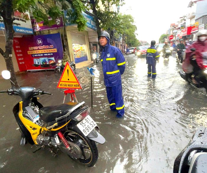 Lực lượng chức năng ứng trực tại khu vực ngập cục bộ, đặt biển cảnh báo hố ga để bảo đảm an toàn cho người tham gia giao thông sáng 16/9.
