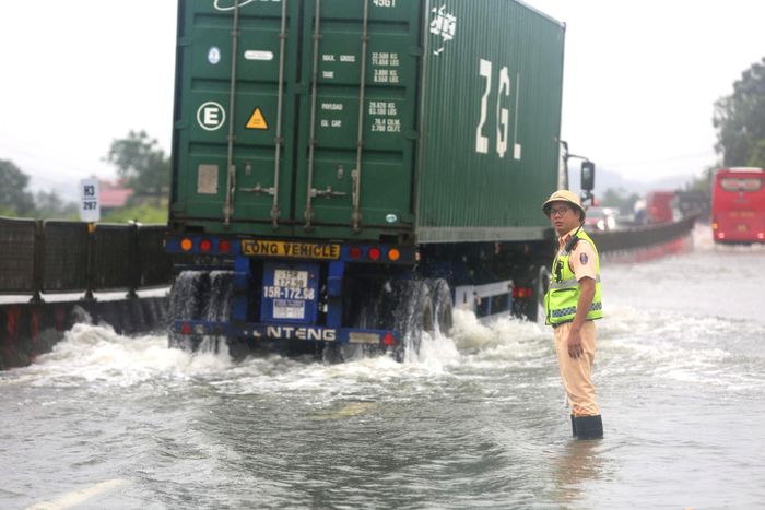 Cảnh sát giao thông Thanh Hóa lội nước phân luồng giao thông trên quốc lộ 1 (Ảnh: P. Tuấn).