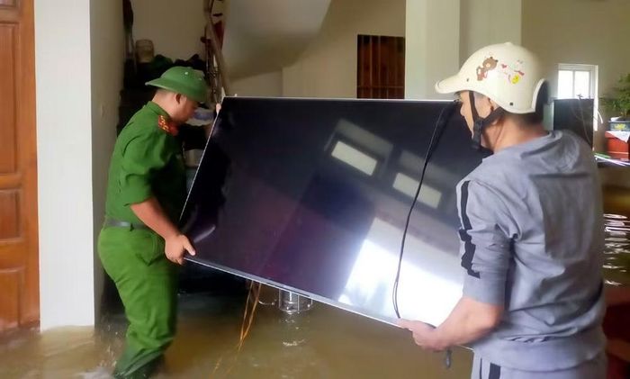 Công an xã hỗ trợ người dân di chuyển đồ đạc tránh ngập lụt.