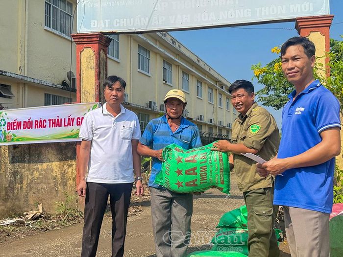 Người dân nhận lại gạo sau khi đem rác đến điểm tập kết.