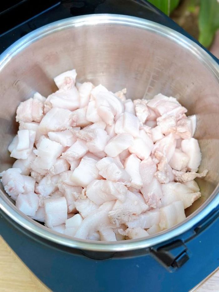 Cắt mỡ lợn (phần mỡ tấm) thành miếng nhỏ, chần qua nước sôi với vài lát gừng để khử mùi tanh. Sau đó, lau khô, cho mỡ vào nồi cơm điện, nhấn nút nấu cơm.