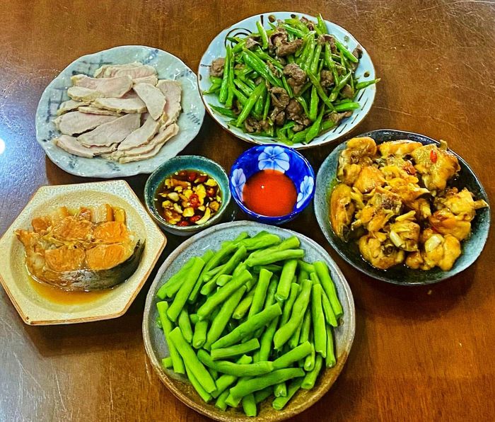 Mâm cơm gia đình ngày mưa với gà rang gừng, thịt bò xào đỗ, thịt luộc, cá kho và đỗ luộc.
