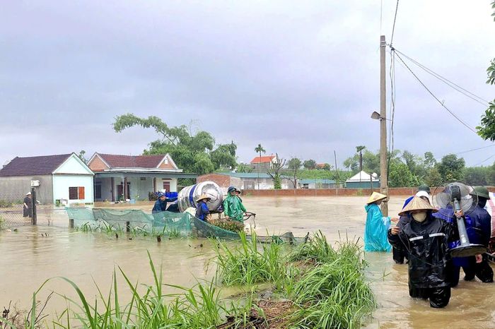 Lực lượng chức năng xã Quỳnh Văn hỗ trợ người dân đưa đồ dùng, lúa gạo ra khỏi nhà bị ngập. Ảnh: D. Lai.