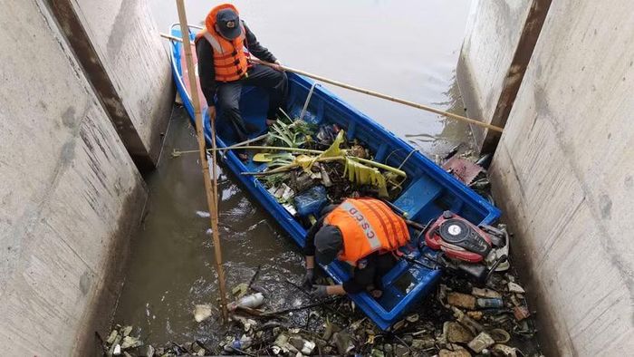 Tổ công tác chèo xuồng cứu hộ chuyên dụng vào tận vòm cống ngầm để bốc dỡ thân cây mục và phế thải nghẽn dòng.