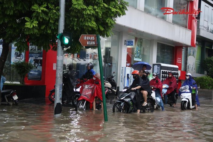 Người dân len lỏi tìm những vị trí ít ngập để di chuyển qua khu vực nước dâng cao.