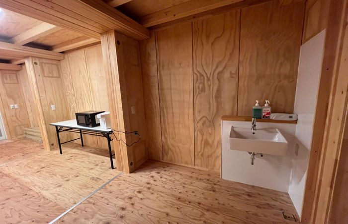  Khu vực bếp và sinh hoạt chung bên trong một dãy container, được trang bị lò vi sóng, ấm đun nước và bồn rửa phục vụ nhu cầu hàng ngày của vận động viên. Ảnh: Quý Lượng. 