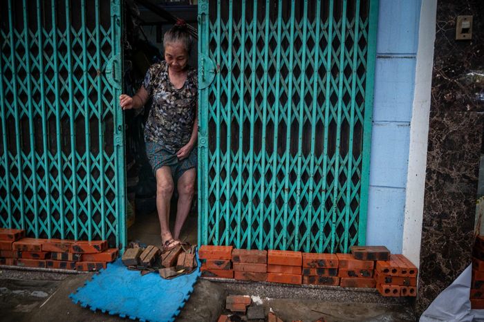  Người dân sinh sống trên đường Lương Thế Vinh xếp gạch trước cửa nhà nhằm ngăn sóng nước tràn vào mỗi khi có phương tiện di chuyển qua. 