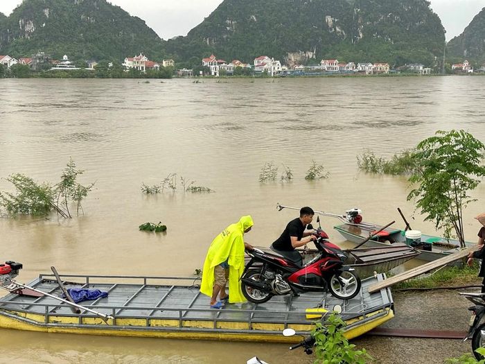 Người dân thôn Kênh Gà (xã Gia Viễn) dùng xuồng chở xe máy vào trong đê tránh lũ