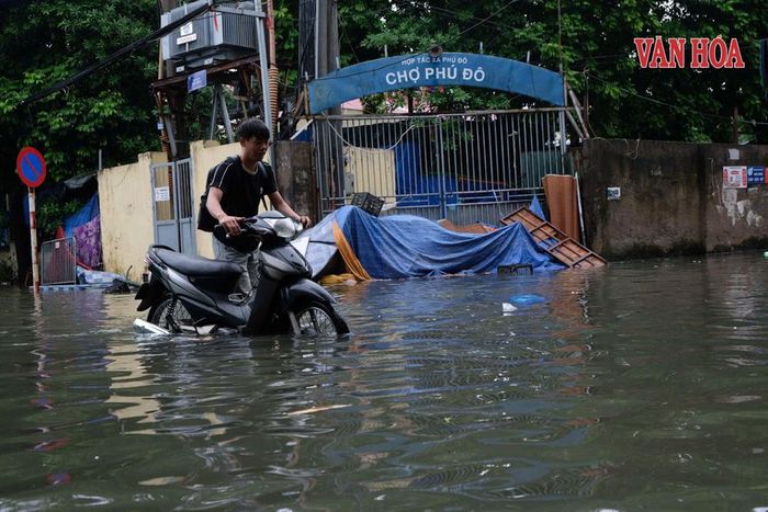 Người dắt người đẩy xe, vượt qua mưa ngập tại khu vực Phú Diễn