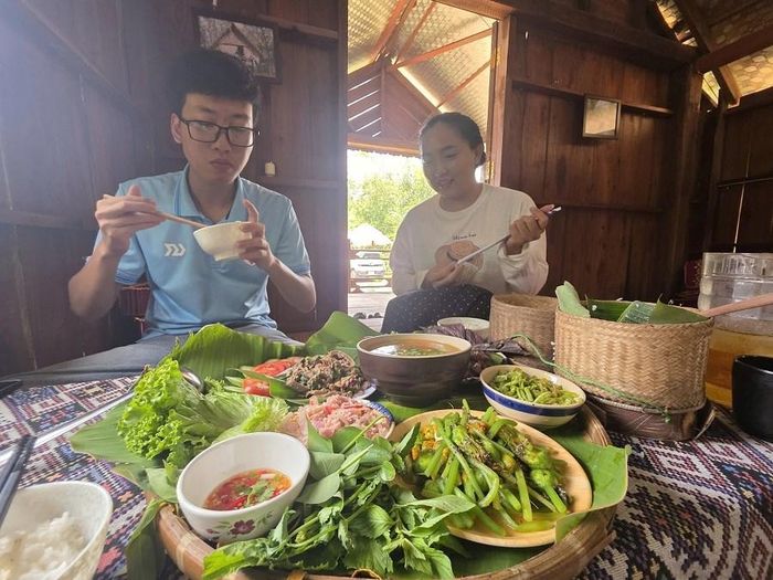 Du khách thích thú khi được thưởng thức ẩm thực của người bản địa trong căn nhà dài của vợ chồng H'Diên
