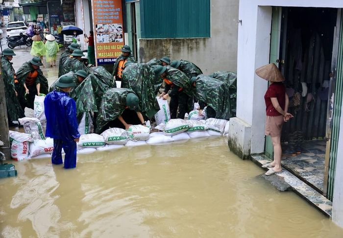 Lực lượng bộ đội hỗ trợ đắp đê bao ngăn nước khu dân cư ven sông Bùi. Ảnh: Nhật Anh - TTXVN