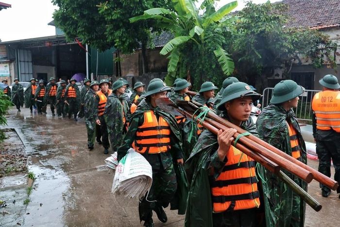 Cán bộ, chiến sĩ Trung đoàn 102, Sư đoàn 308 mang theo bao vật liệu, chuẩn bị đắp đê ngăn nước lũ tại xã Quảng Bị. Ảnh: Phạm Tuấn Anh - TTXVN