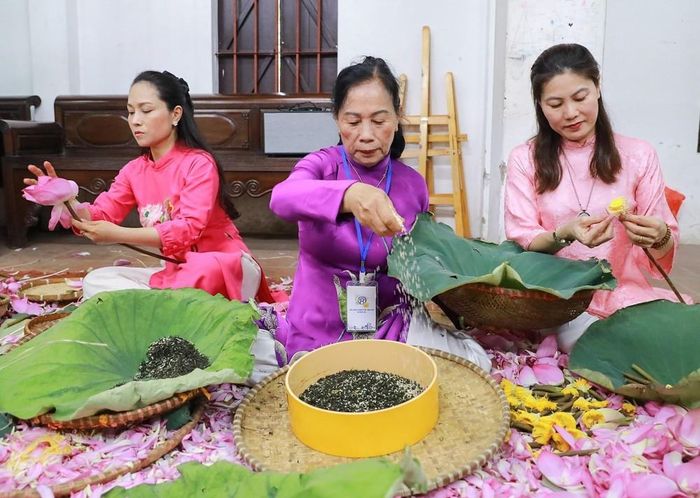 Nghệ nhân ướp trà sen Lê Thị Hiền (giữa) cùng các con thực hiện các công đoạn ướp sen truyền thống. Ảnh: Khánh Hoà - TTXVN