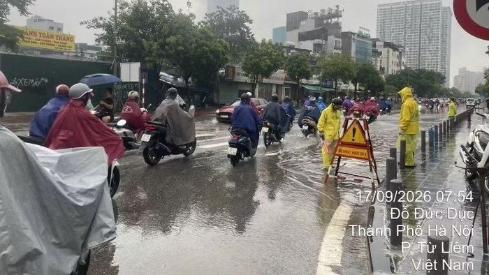 Công nhân thoát nước ứng trực, khơi thông thoát nước sáng 17/9 tại điểm ngập nước trên phố Đỗ Đức Dục, hướng dẫn giao thông cho người dân. (Ảnh: THU THỦY)