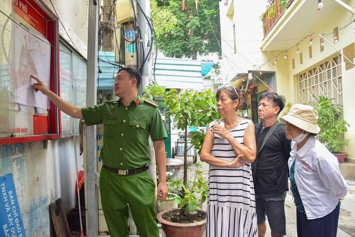 Công an phường Cầu Ông Lãnh tuyên truyền cho cư dân về Dự án chỉnh trang khu Mả Lạng. (Ảnh: TRÍ ĐỨC)