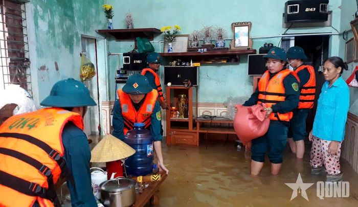 Cán bộ, nhân viên Ban CHQS xã Hoằng Sơn hỗ trợ người dân di chuyển tài sản, nhu yếu phẩm ra khỏi khu vực bị ngập.