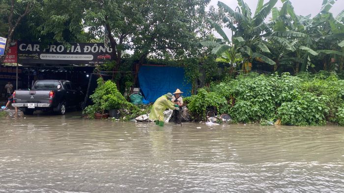 Công nhân thoát nước Hà Nội mở và dọn dẹp rác tại các miệng phai, cống để tiêu thoát nước lúc 9 giờ ngày 17-9. Ảnh: PHÚC HẬU
