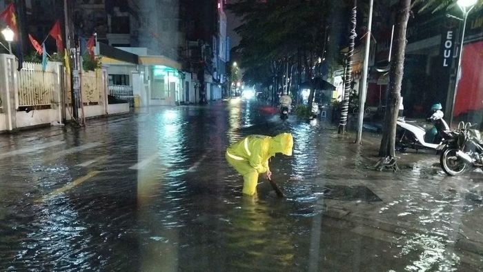 Các nhân viên thoát nước xử lý rác tại các hố ga để dòng nước thoát đi.