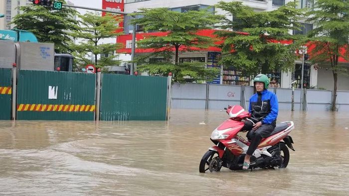 Một người dân chỉ biết ngồi một chỗ trên xe vì bất lực không thể di chuyển qua khu vực ngập sâu. Ảnh: Đình Tuệ.
